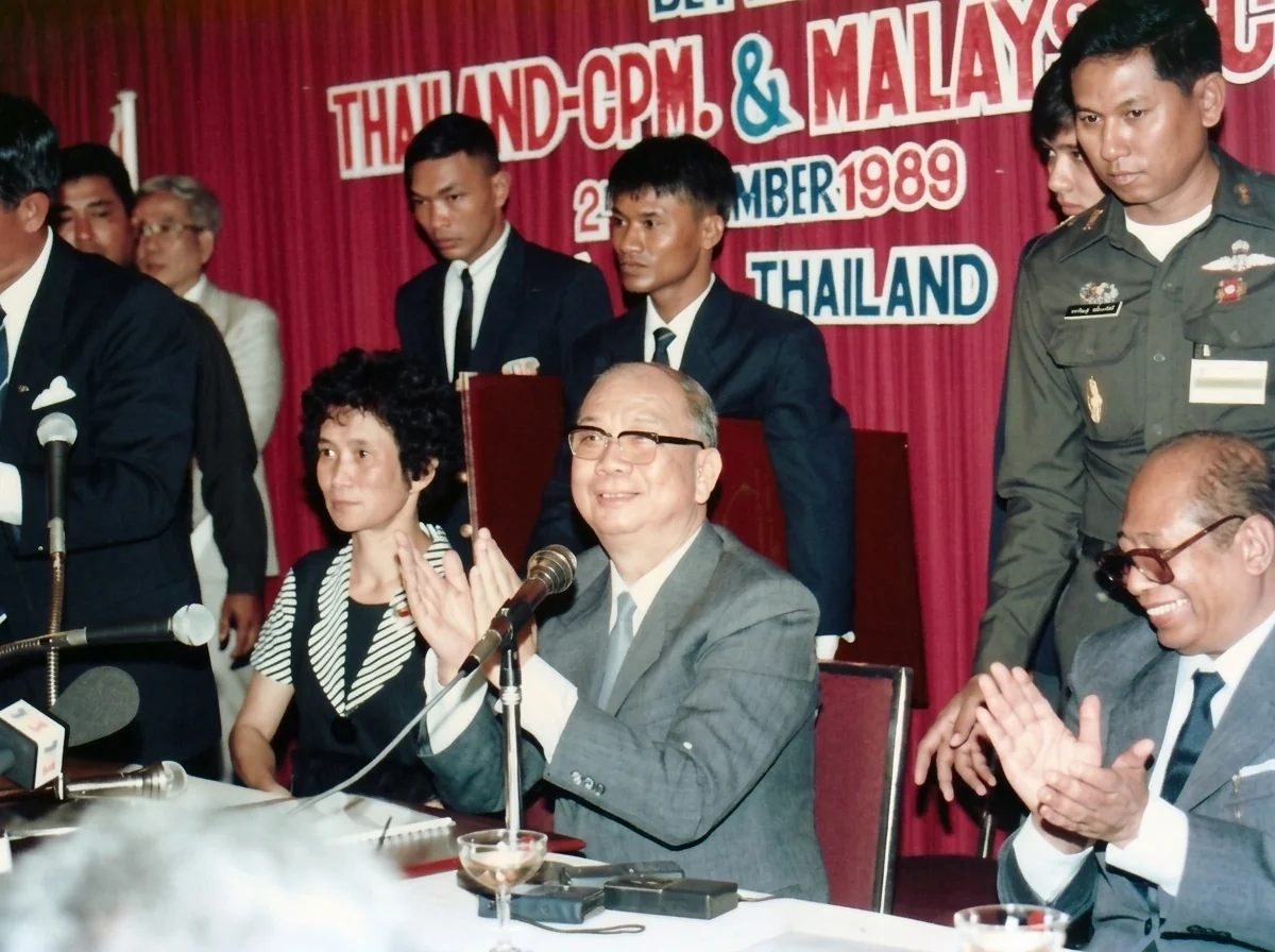 1989年12月2日合艾签署大典主席台上，马共中央总书记陈平（中）与马共中央主席阿都拉·西迪（右）抚掌致意