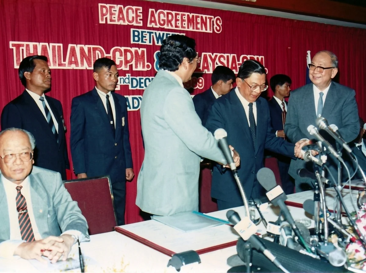 1989年12月2日协议签署完毕后，旺西迪（左二）、差瓦立上将（右二）与陈平（右一）起立握手，左一就座者为泰国内政部常务次长阿内·西提巴萨