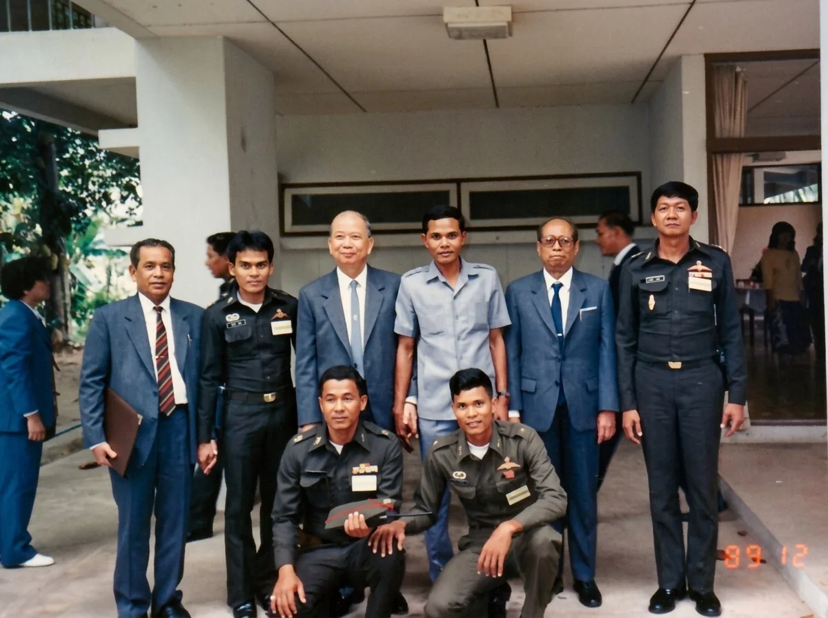 1989年12月2日合艾下榻驻地门前，拉昔·迈丁（后排左一）、陈平（后排左三）、阿都拉·西迪（后排右二）与泰军第四军区官兵合影（左端廊柱旁侧立者为陈再润）