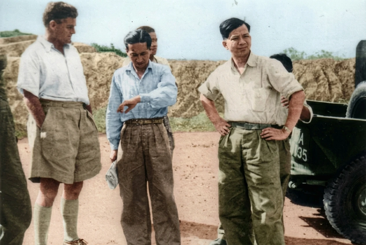 1955年12月华玲和谈会场外：昔日136部队盟友约翰·戴维斯（左）与陈田（中）、陈平（右）在吉普车与土垒旁交谈历史实照