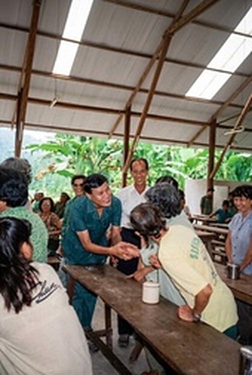 和平村医疗与物资发放点：泰方随行医护与工作人员在木棚下为村民提供健康检查与生活用品。