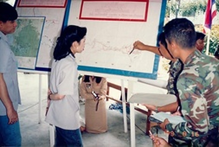 1993年8月：朱拉蓬公主驻足于大型规划地图图板前，听取军方工程人员用教鞭讲解和平村道路网与农田水利布局。