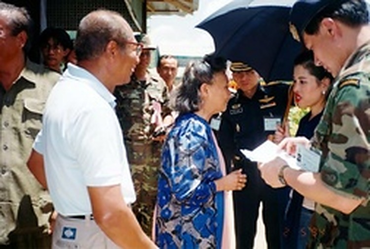 1994年2月5日：朱拉蓬公主在雨伞遮护下与和平村长者亲切交谈，随行军官在旁记录。