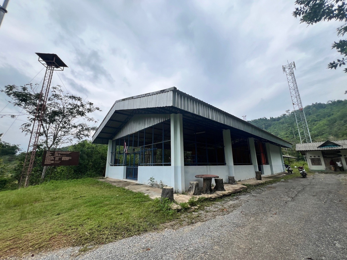 也哈和平村（第11朱拉蓬公主发展村）现代化社区礼堂与通讯塔：宽敞的蓝白公共活动中心旁已架设起无线通讯基站。