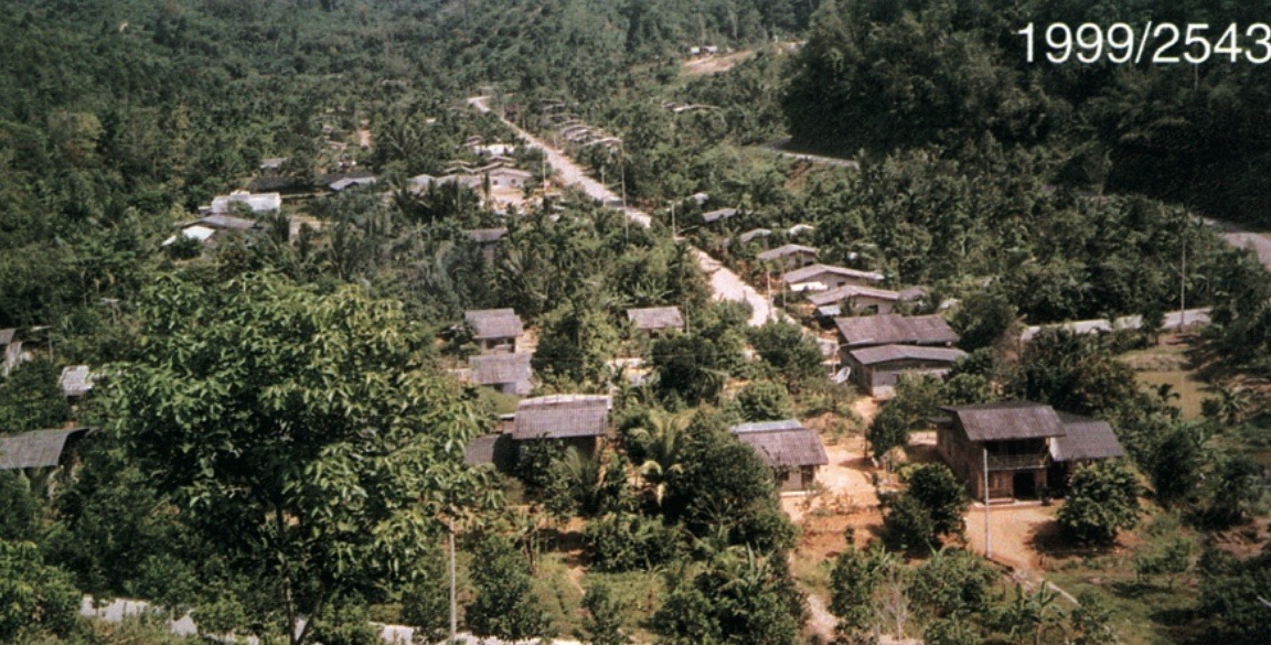 苏基林和平村（Sukhirin Peace Village，第12朱拉蓬公主发展村 / Ban Chulabhorn Patana 12）1999年（佛历2543年）山谷全景俯瞰：原马来亚人民军第十二支队与第十支队部分指战员在此垦荒建村，笔直的村道两旁整齐排列着灰瓦民居，掩映在苍翠的陶公府群山之中。