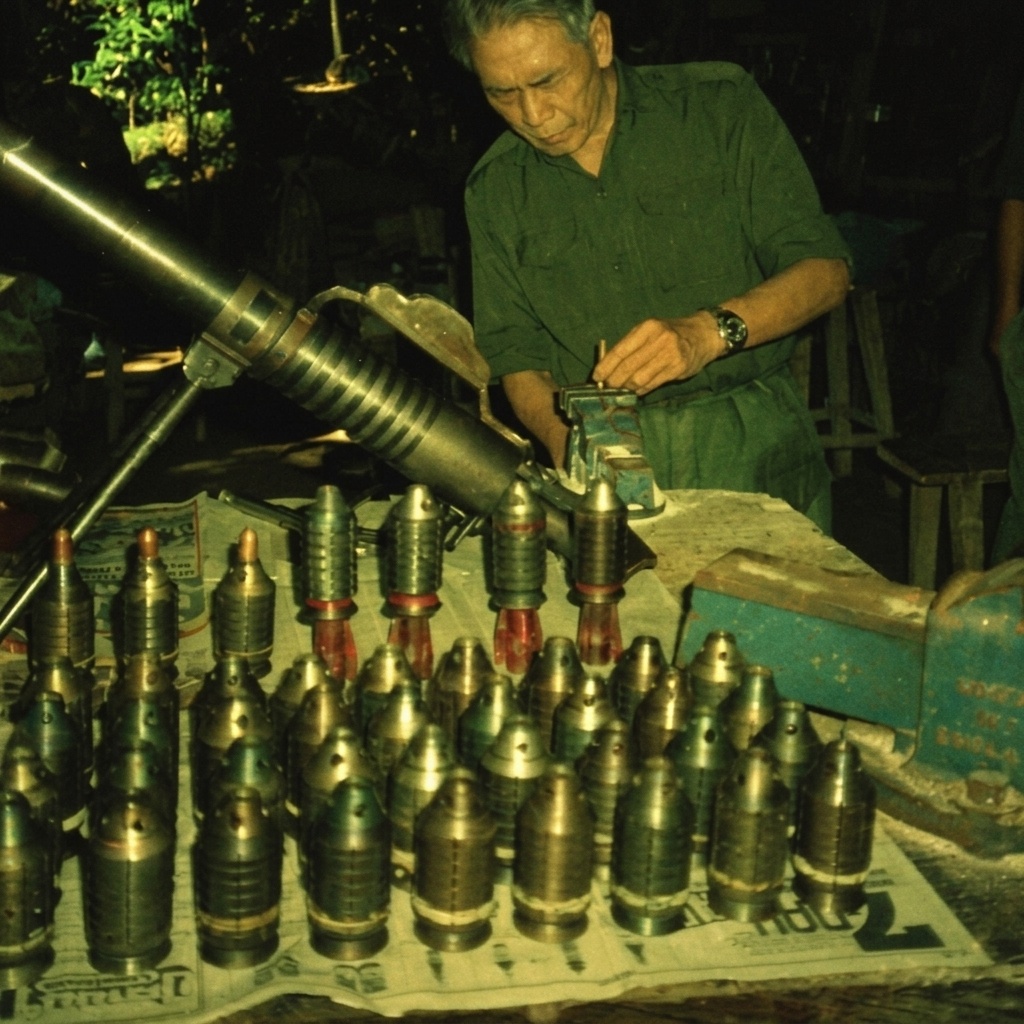 1989年8月7日，军械技术人员在密林地下兵工厂工作台前使用台虎钳组装自制地雷与迫击炮弹，台面整齐排列着数十枚铸铁弹体。