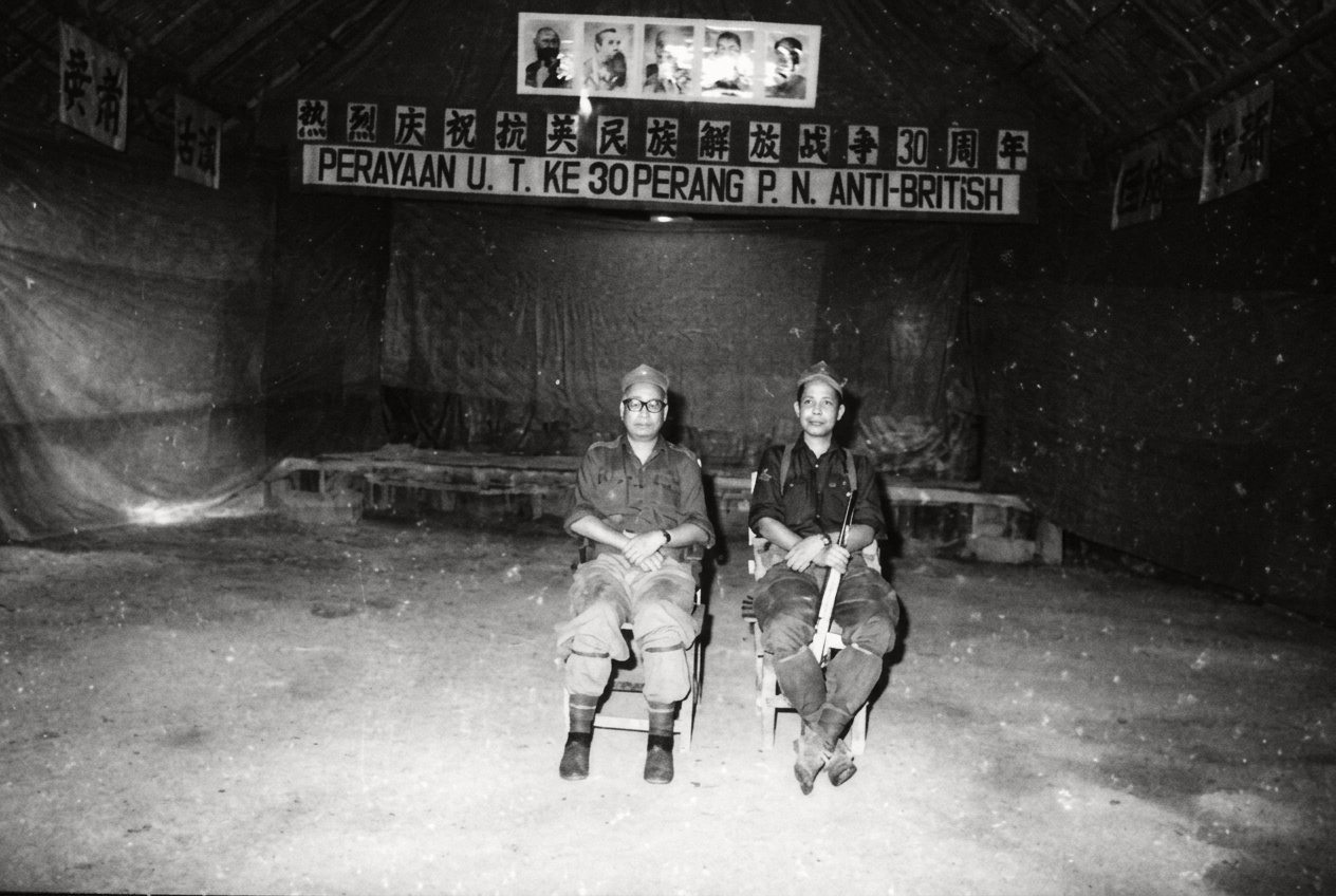 1978年8月4日，马共中央委员、第十支队领导人阿布·沙玛（Abu Samah，左）与第十支队指挥骨干卡玛（Kama，右，持卡宾枪）在“热烈庆祝抗英民族解放战争30周年”华巫双语会场留影。